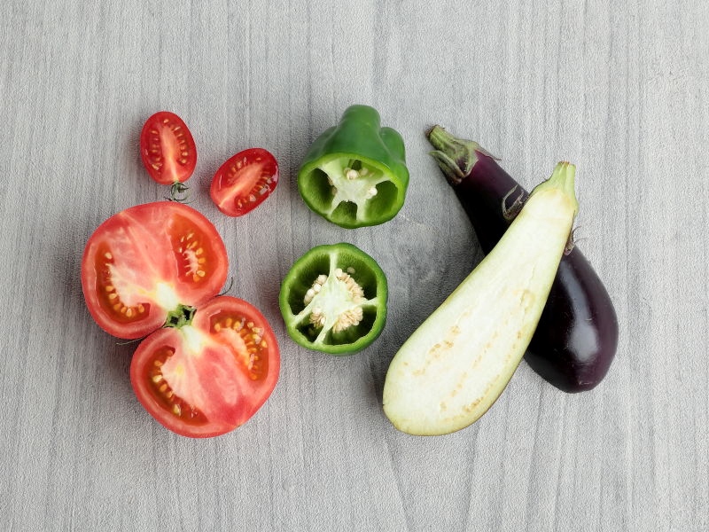 カットされた夏野菜が４種類、トマト、ミニトマト、ピーマン、ナスが並んでいる様子